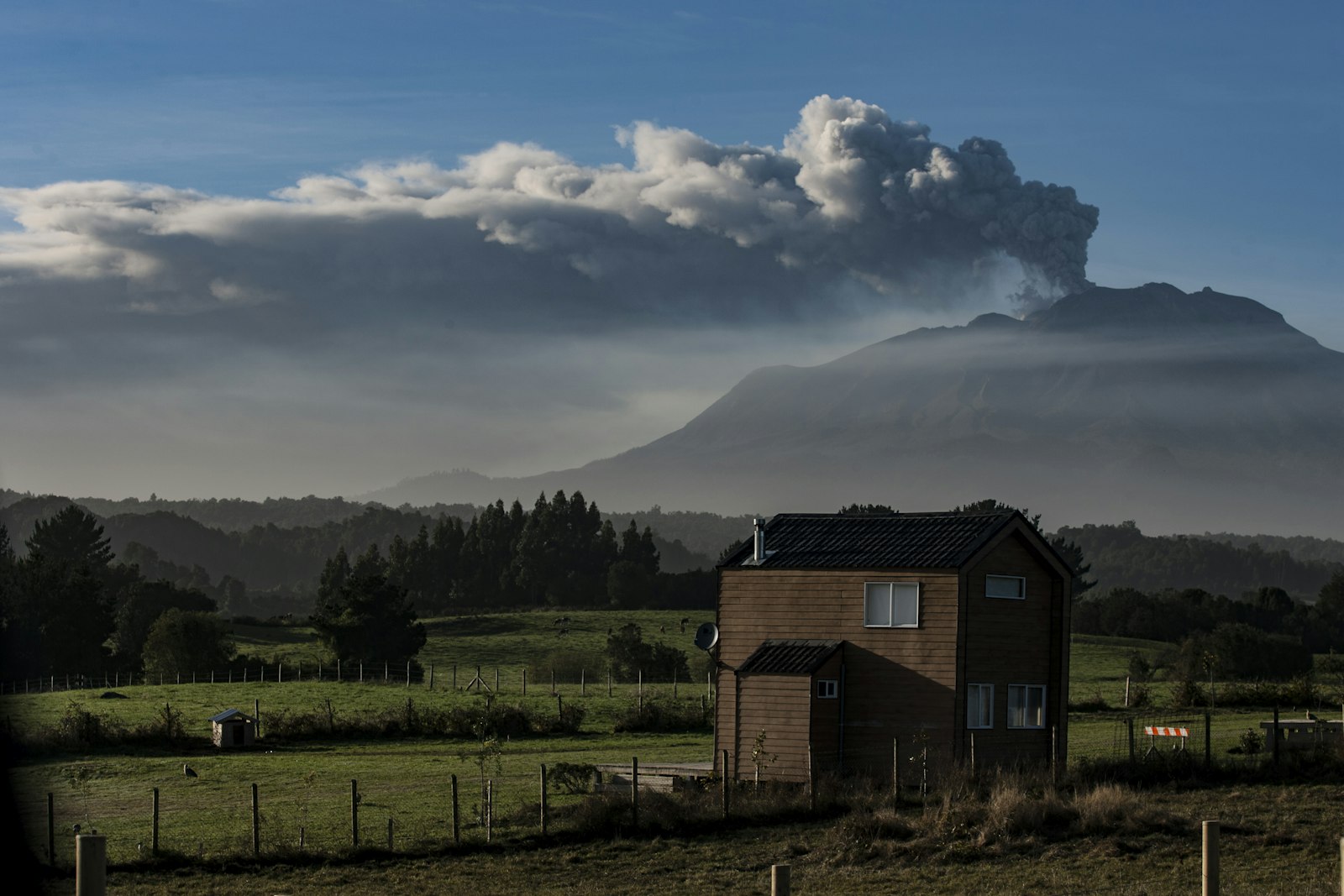 Parcela con casa y campo verde, con volcán al fondo, en Chile